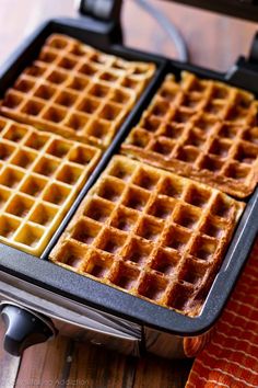 two waffles sitting on top of each other in a metal pan next to a red and orange towel