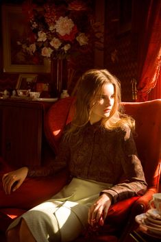 a woman sitting in a red chair next to a window