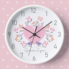 a white clock with pink heart and flowers on it's face against a polka dot background