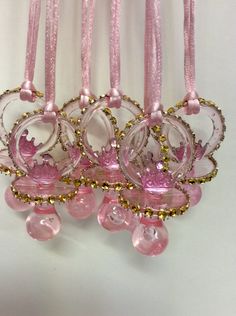 pink and gold hair combs are hanging on a white wall, with beads attached to them