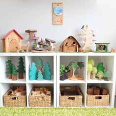 there are many toy houses and trees on the shelves in this playroom with toys