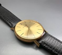 A fairly rare men's (unisex) 14k solid gold Swiss DUGENA watch with the classic Bauhaus look, with a gold punch on caseback, manual winding watch with a gold color dial, gorgeous, completely original, with lizard calf leather strap. The reverse is engraved, the watch is in good working condition, almost unworn pristine condition considering age, no scratches on the glass and case. Dates: 1979 Case size: 34 mm Total weight: approx. 29g A true classic, worth collecting! PLEASE NOTE: ALL MY WATCHES ARE SOLD IN WORKING CONDITION AND TESTED TO ENSURE THEY ARE KEEPING REASONABLY ACCURATE TIME. TIMEKEEPING MAY VARY AND WILL NOT BE AS ACCURATE AS A NEW WATCH. AS THEY ARE VINTAGE PIECES NO OTHER GUARANTEES CAN BE GIVEN OR IMPLIED. I DO NOT SERVICE MY WATCHES PRIOR TO SALE, AS THIS WOULD ADD SIGNIFI Antique Gold Watch For Business, Gold Engraved Business Watches, Engraved Gold Business Watches, Business Watches In Yellow Gold With Gold Clasp, Gold Punch, New Watch, Vintage Pieces, Wrist Watches, Slovenia