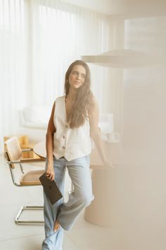 a woman standing in front of a table holding a folder and smiling at the camera