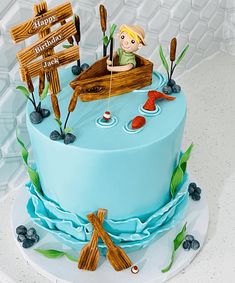 there is a blue cake decorated with an image of a boy in a boat on the water