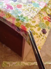 a pair of scissors sitting on top of a table covered in colorful flowers and leaves