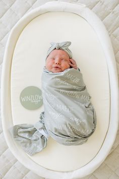 a baby wrapped in a blanket on top of a white bed with the words winnow written on it