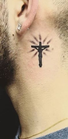 a man with a cross tattoo on his neck and behind the ear is a black outline