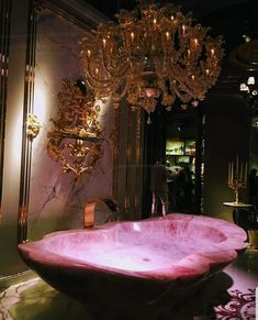 a pink bathtub in the middle of a room with chandelier above it