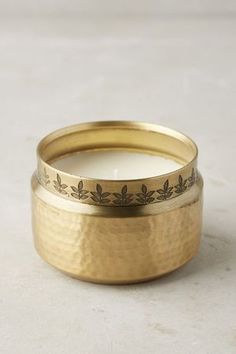 a close up of a gold ring with leaves on it and a candle in the middle