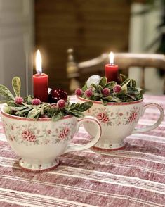 two coffee cups with candles in them sitting on a table