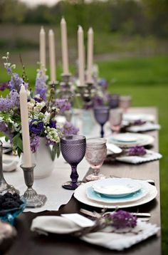 the table is set with purple and white plates, silverware, and lavender centerpieces