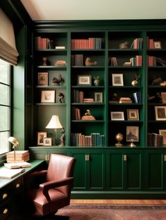 an office with green bookshelves and leather chair