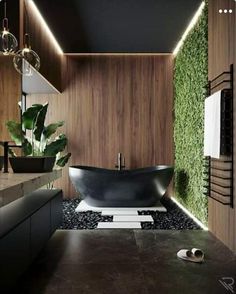 a black bath tub sitting in a bathroom next to a sink and mirror with plants growing on the wall