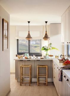 a kitchen with two stools next to an island