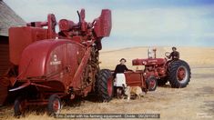 two men and a dog standing in front of a red farmall tractor with large wheels