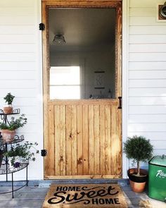 a welcome mat on the front steps of a house with potted plants and an open door