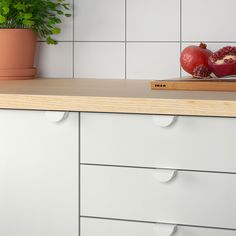 two pomegranates sit on top of a cutting board next to a potted plant