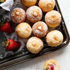 powdered sugar covered donuts and strawberries on a baking sheet