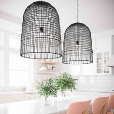 two pendant lights hanging over a kitchen table with chairs and potted plants on the counter