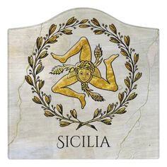 a white marble plaque with the word siclia in gold and an image of a naked woman surrounded by leaves