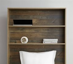 a bed with white sheets and pillows in a wooden bookcase next to a wall