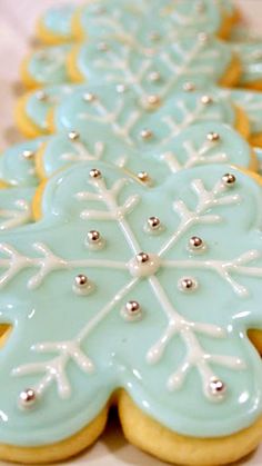 decorated cookies are lined up on a white plate with silver beaded trimmings