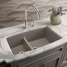 a kitchen sink sitting under a faucet on top of a marble countertop