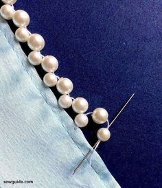 a close up of a piece of cloth with pearls on it and a needle in the middle