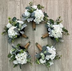 flowers arranged in the shape of a wreath on a wooden floor with greenery around them