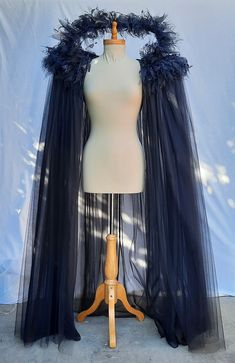 a mannequin wearing a black cape with feathers on it