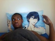 a man laying on top of a bed next to a pillow with an anime character on it