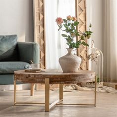 a living room with a couch, coffee table and vase on the floor in front of a mirror