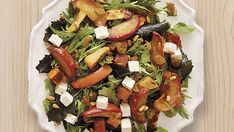 a white plate topped with salad on top of a wooden table