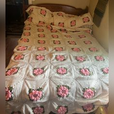 a crocheted bedspread with pink flowers on it