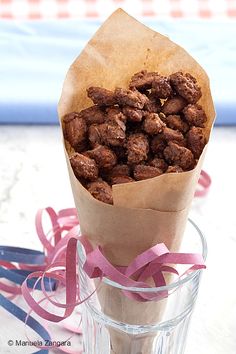 a paper bag filled with nuts sitting on top of a table next to a ribbon