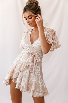 Buy the Cami Angel Sleeve Faux Wrap Dress Nude | Selfie Leslie Summer V-neck Lace Dress With Ruffles, Feminine Fitted Lace Dress With Ruffle Hem, Flirty Lace Dress For Garden Party, Party Dress With Flutter Sleeves And Lace Trim, Chic Lace Dresses With Flutter Sleeves, Flowy Lace Dress With Ruffles, Beige Lace Dress With Ruffles, Spring Flowy Dress With Scalloped Lace, Flowy Scalloped Lace Dresses For Spring