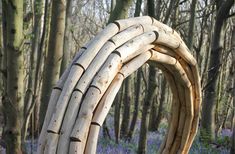 a wooden sculpture in the middle of a forest filled with bluebells and trees