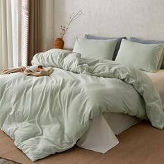 an unmade bed with green sheets and pillows