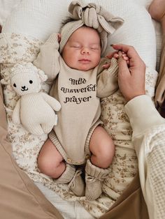 Celebrate your little miracle with our beautiful beige embroidered knit romper, designed to keep your baby nice and cozy! Crafted from soft, breathable fabric, this romper features long sleeves for extra warmth, making it perfect for any season. The standout detail of this romper is the sweet embroidery that reads "little answered prayer" in a lovely neutral brown hue, adding a heartfelt touch to your baby’s wardrobe. Designed with practicality in mind, the romper includes buttons for easy diaper changes, allowing you to tend to your little one effortlessly. The relaxed fit ensures plenty of room for movement, so your baby can crawl, wiggle, and explore with ease. Mix and match with our matching booties, beanie or topknot! Crochet Baby Headband, Sweet Embroidery, Knit Bow, Baby Headbands Crochet, Ribbed Knit Bodysuit, Knit Romper, Family Outings, Knitted Booties, Knit Headband