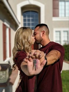 a man and woman holding keys in front of a house