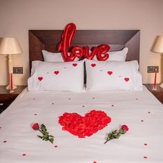 the bed is decorated with red roses and love balloons