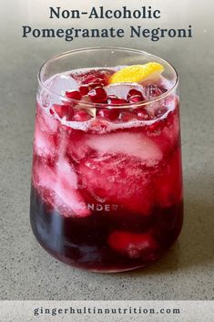 a red drink in a glass with ice and cranberries on the rim, next to a lemon wedge