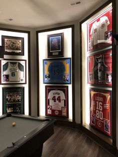 a pool table in front of several framed sports memorabilia