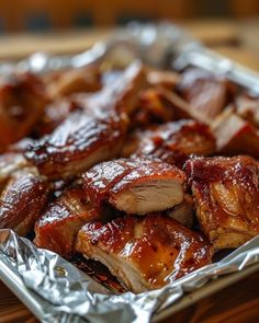 meat wrapped in tin foil sitting on top of a wooden table