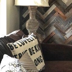 a lamp sitting on top of a wooden table next to a brown couch with pillows