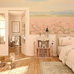 a bedroom decorated in pastel tones with flowers painted on the wall and wooden floors