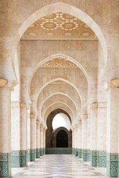 an empty hallway with tiled floors and arches