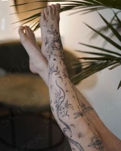 a person with tattoos on their arms and legs sitting next to a potted plant