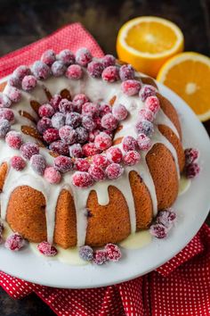 a bundt cake with icing and fresh berries on top sits on a white plate