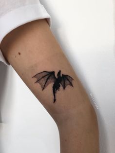 a small black bat tattoo on the arm